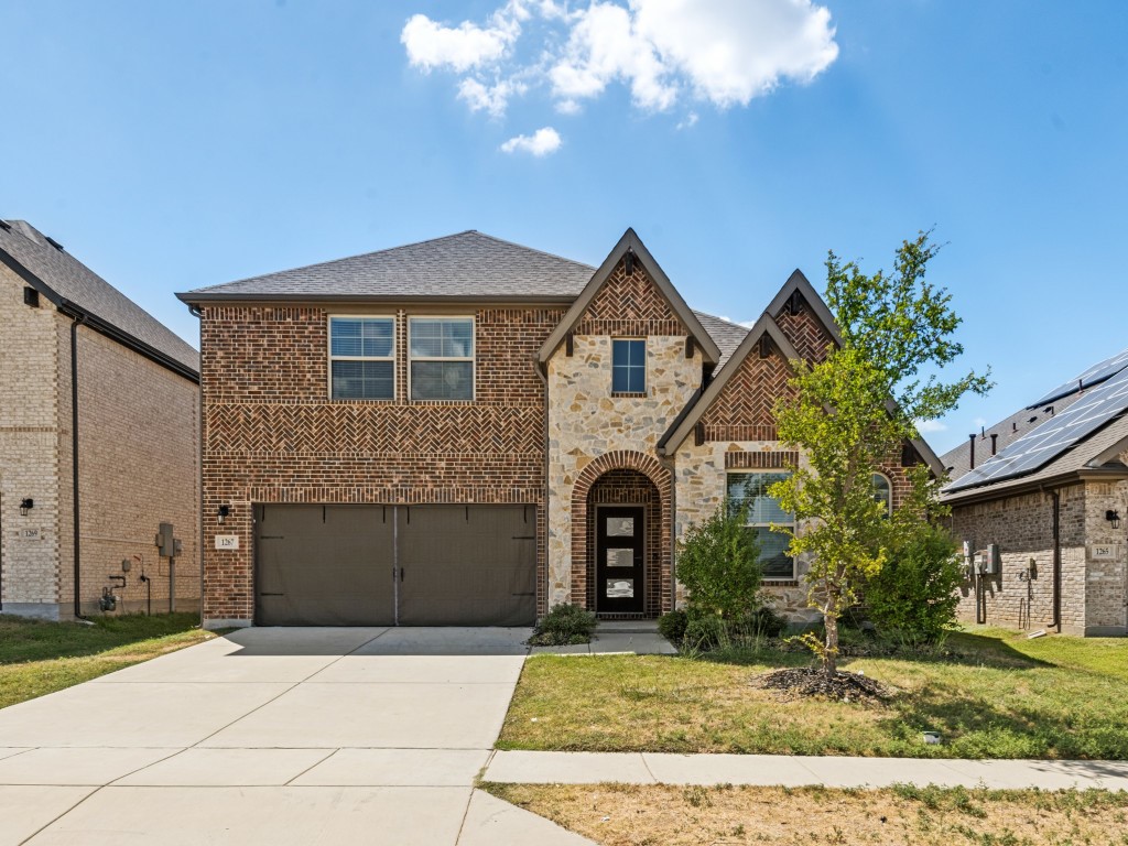Two-story brick-and-stone home with a two-car garage, arched entry, and broad driveway.