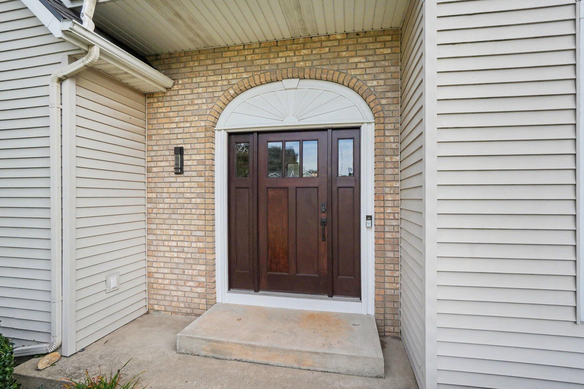 Home entrance with dark double doors, arched transom, and tan brick surround.