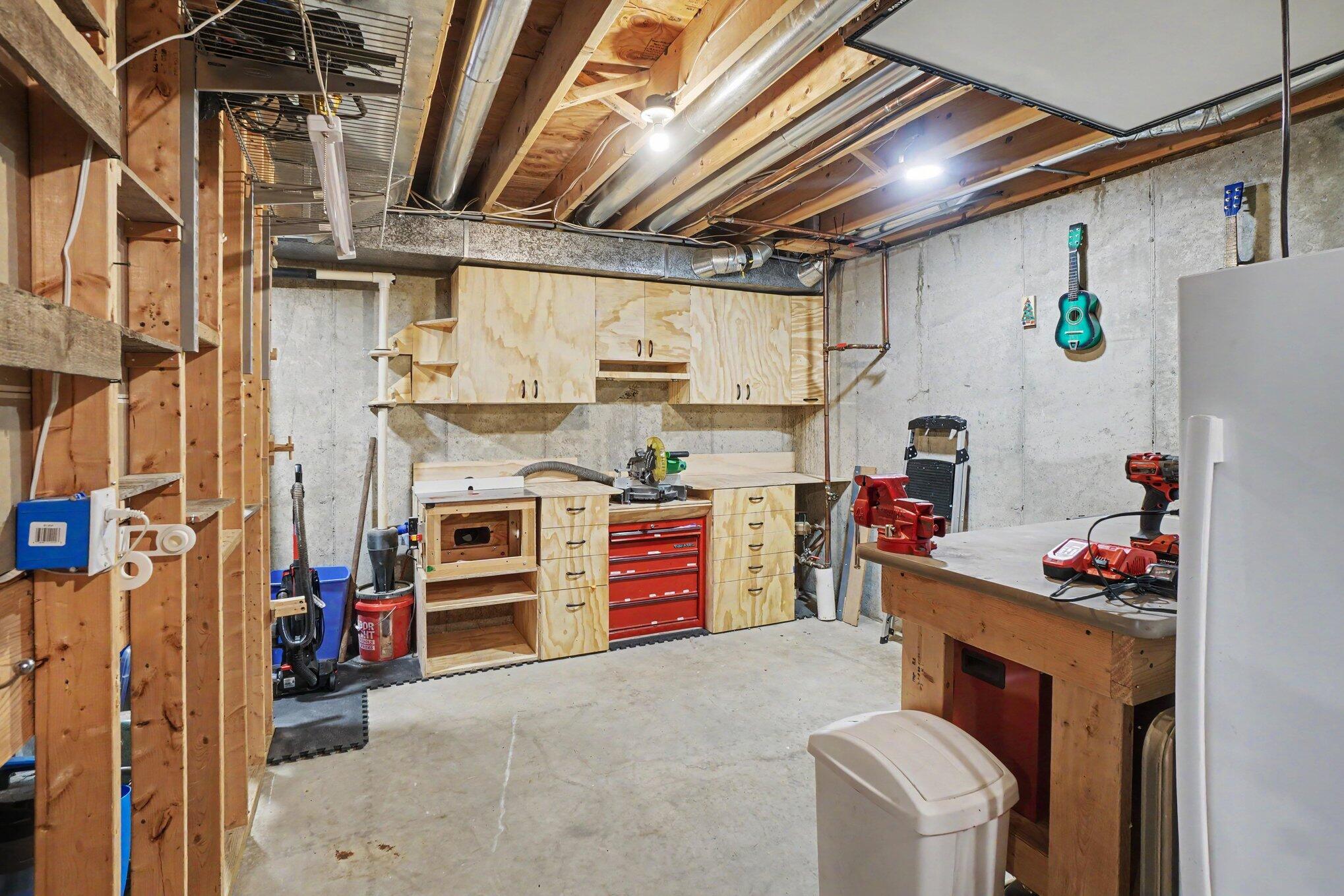 Basement workshop with plywood cabinets, workbenches, and a red tool chest.