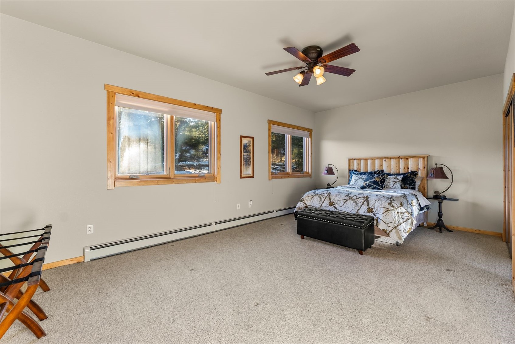 Spacious bedroom with a king bed, wood-trimmed windows, and a ceiling fan.