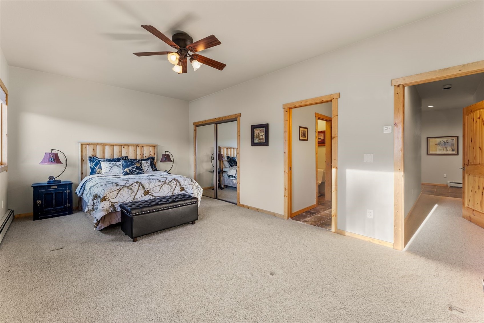 Spacious bedroom with a king bed, mirrored closet doors, and light wood trim.