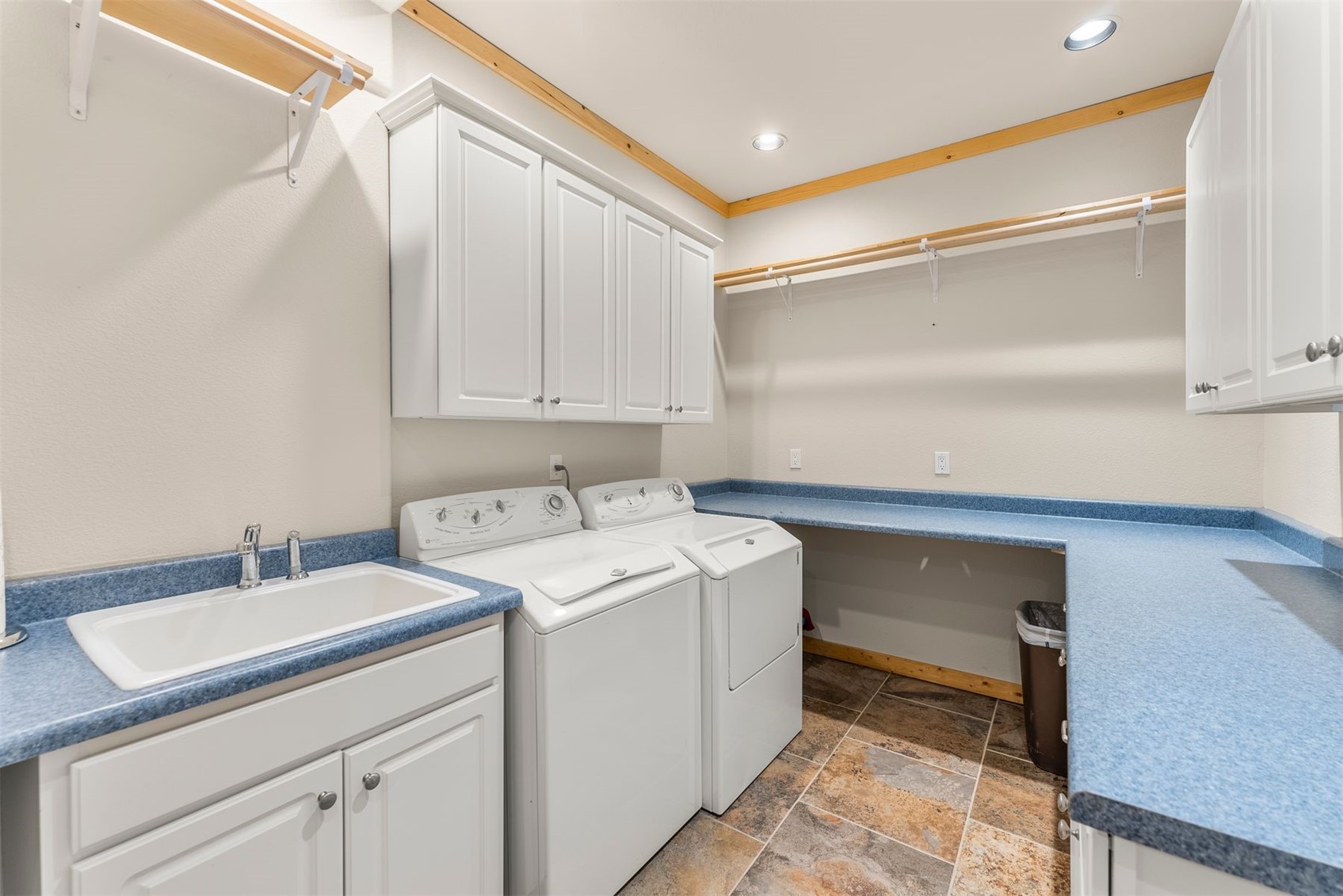 Laundry room with washer and dryer, utility sink, white cabinets, and blue countertops.