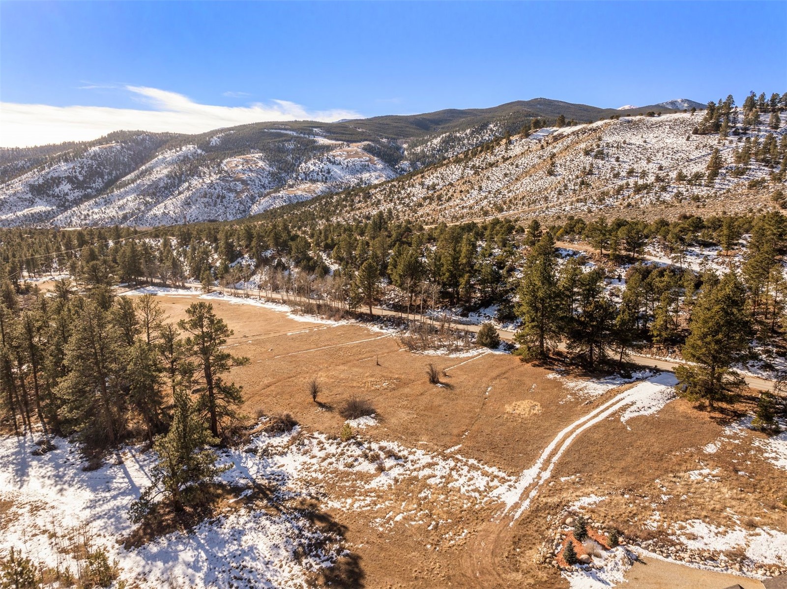 Aerial view of open acreage with scattered pines and snow-dusted mountain ridges near Salida.