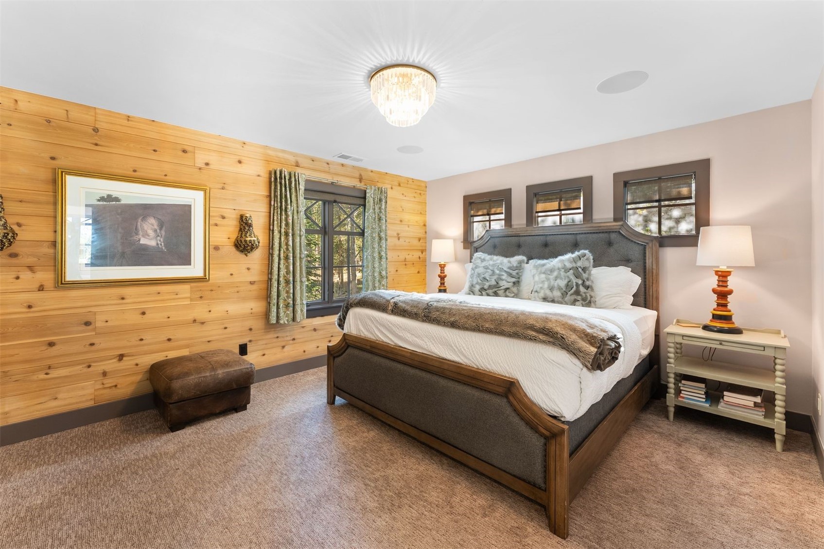 Bedroom with a wood-paneled accent wall, large bed, and chandelier.