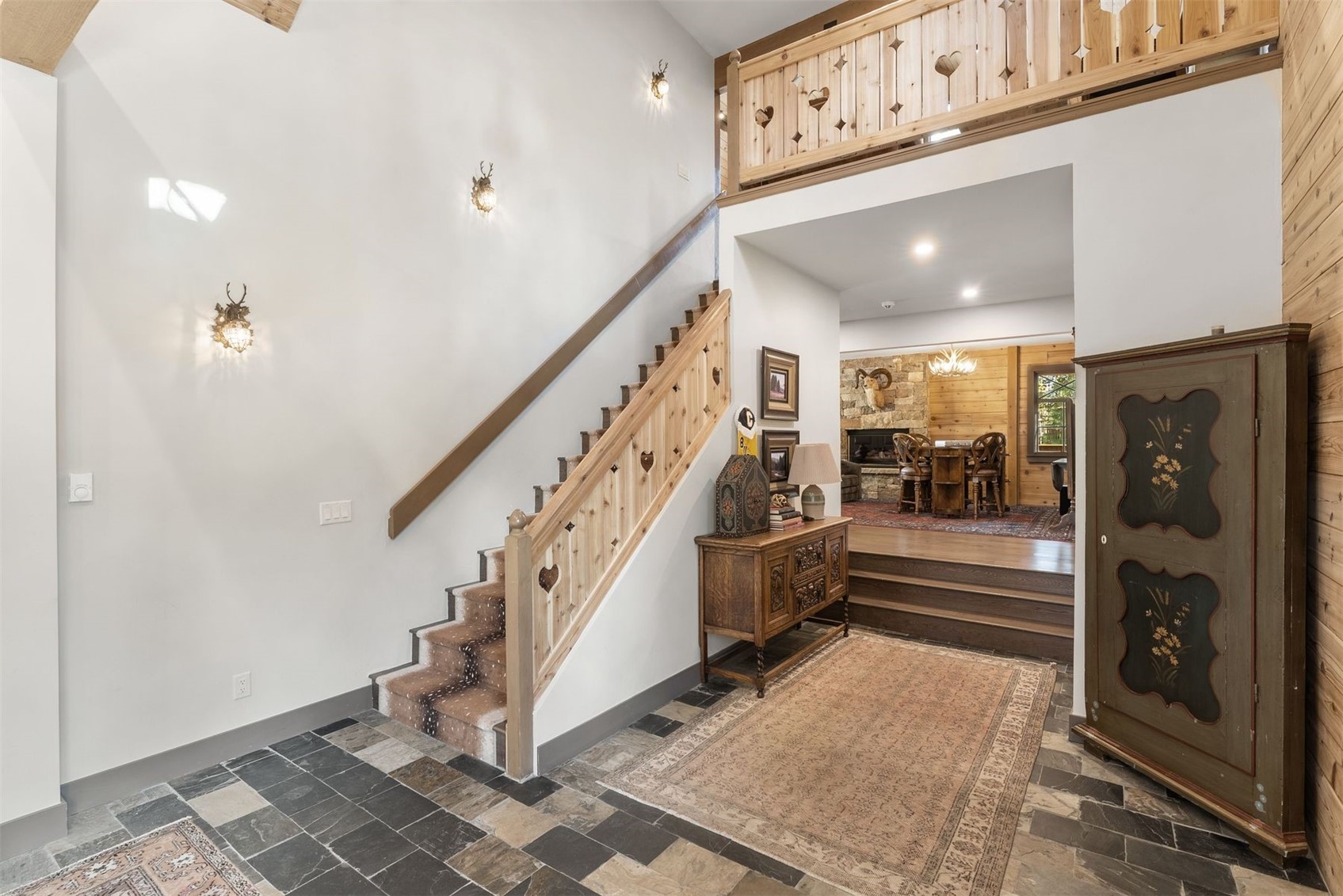 Furnished entry foyer with a heart-cutout wood staircase, slate tile, and upper landing.