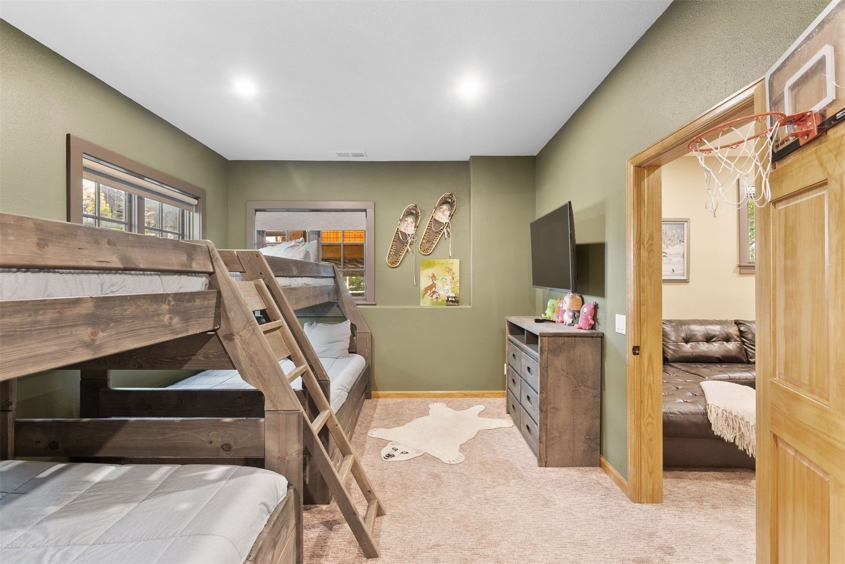 Bedroom with rustic wooden bunk beds, a mounted TV, and a basketball hoop over the doorway.