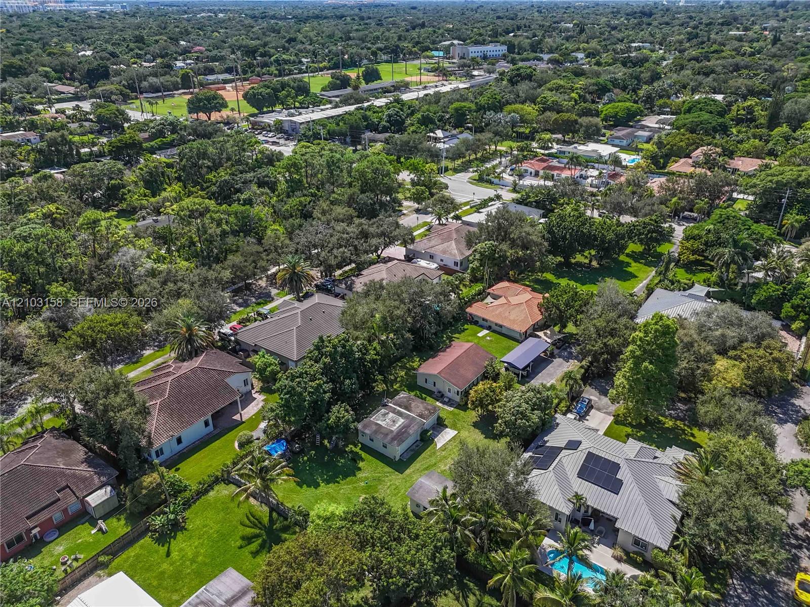 Aerial view of a leafy neighborhood with single-family homes and recreation fields.