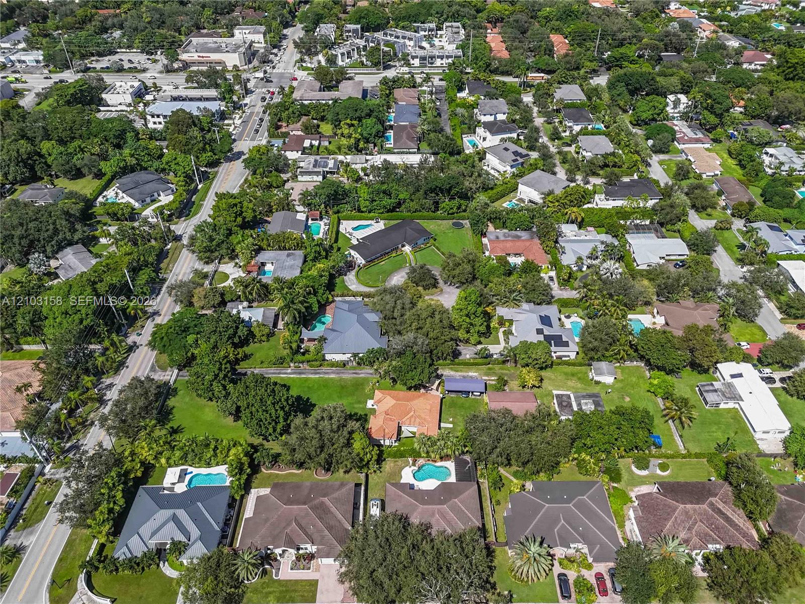 Aerial view of homes and tree-lined streets, with swimming pools and landscaped yards.