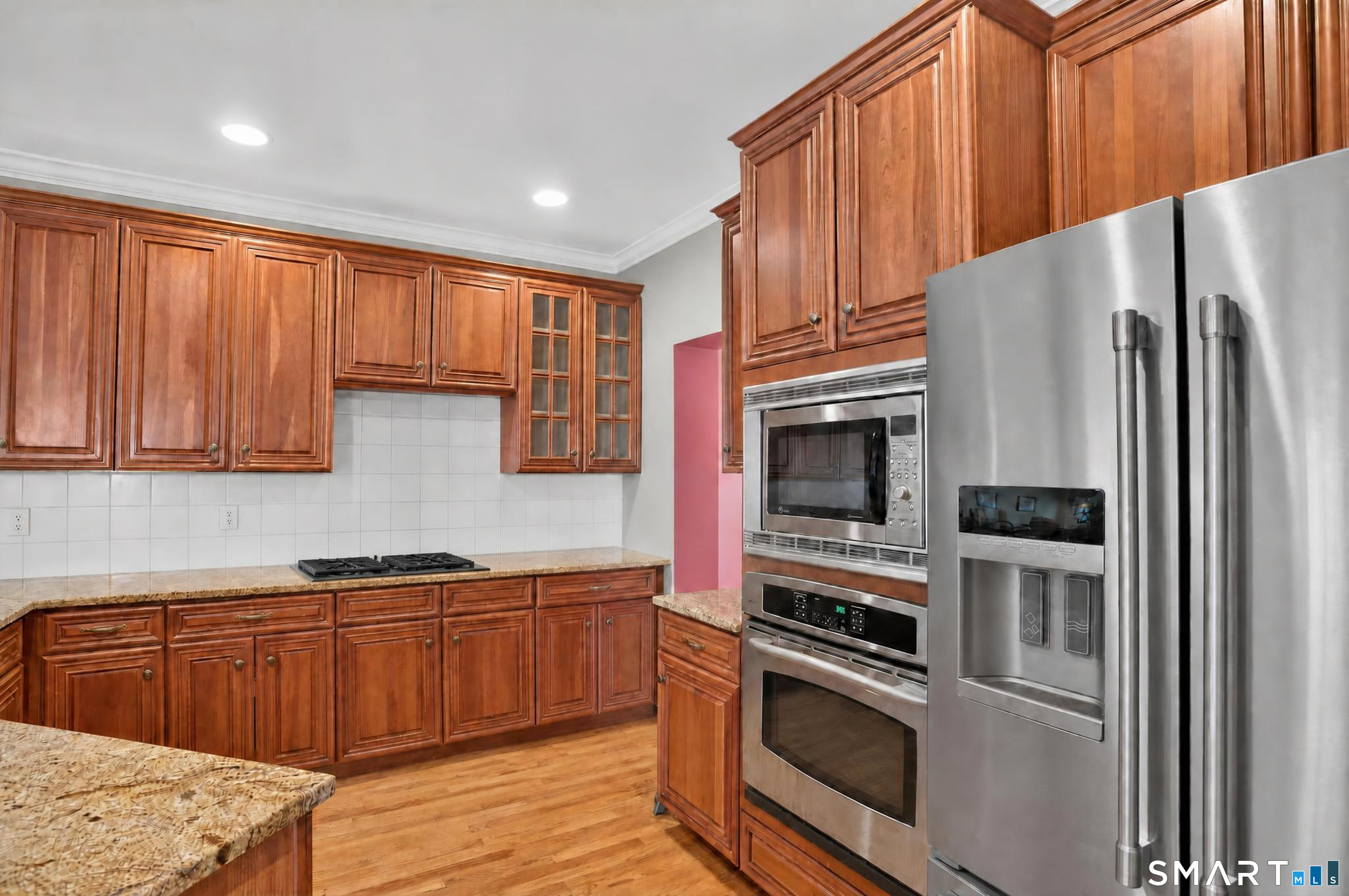 Kitchen with cherry cabinets, granite counters, hardwood floors, and stainless steel appliances.
