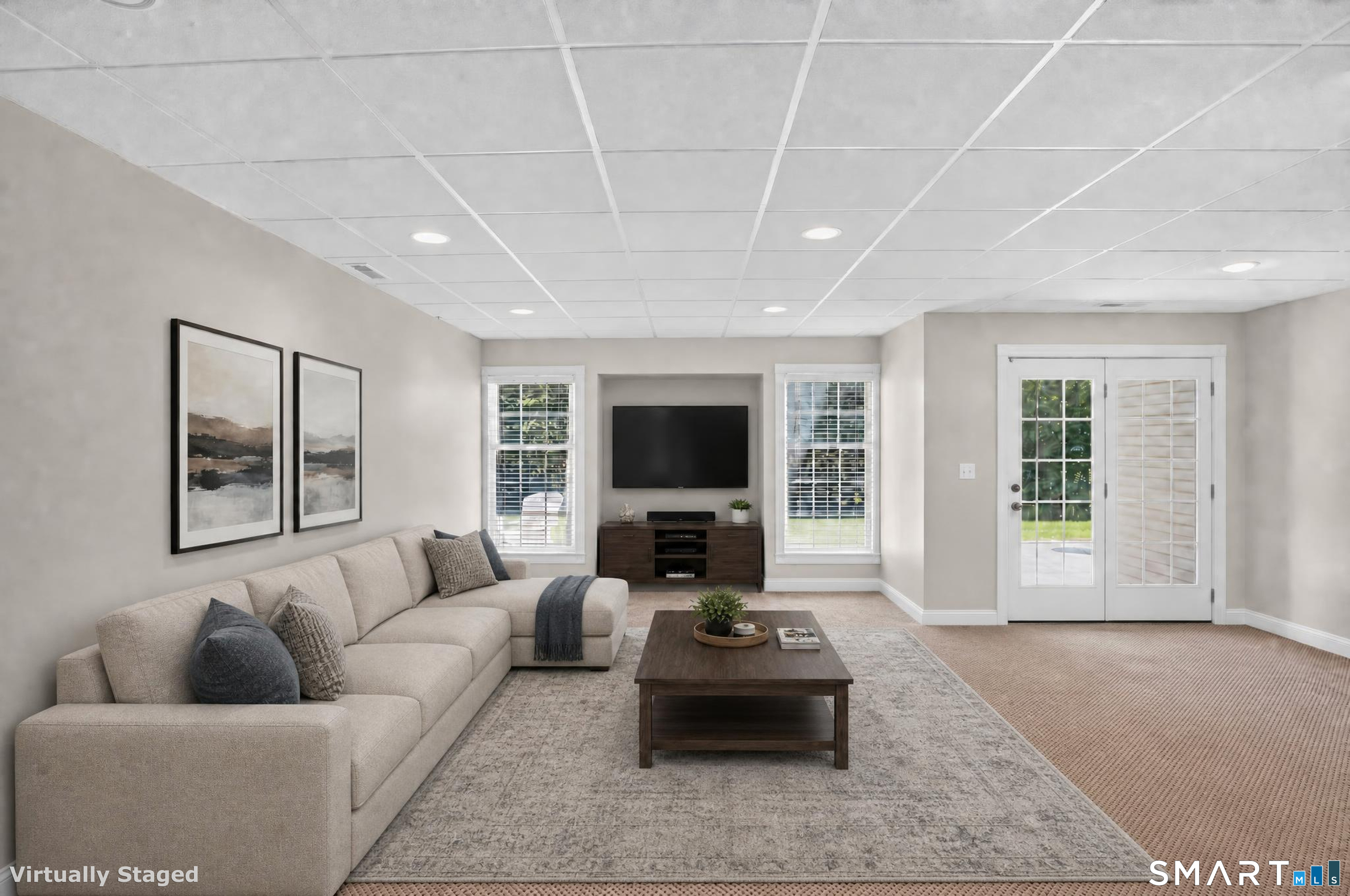 Living room with a beige sectional, wall-mounted television, and French doors.