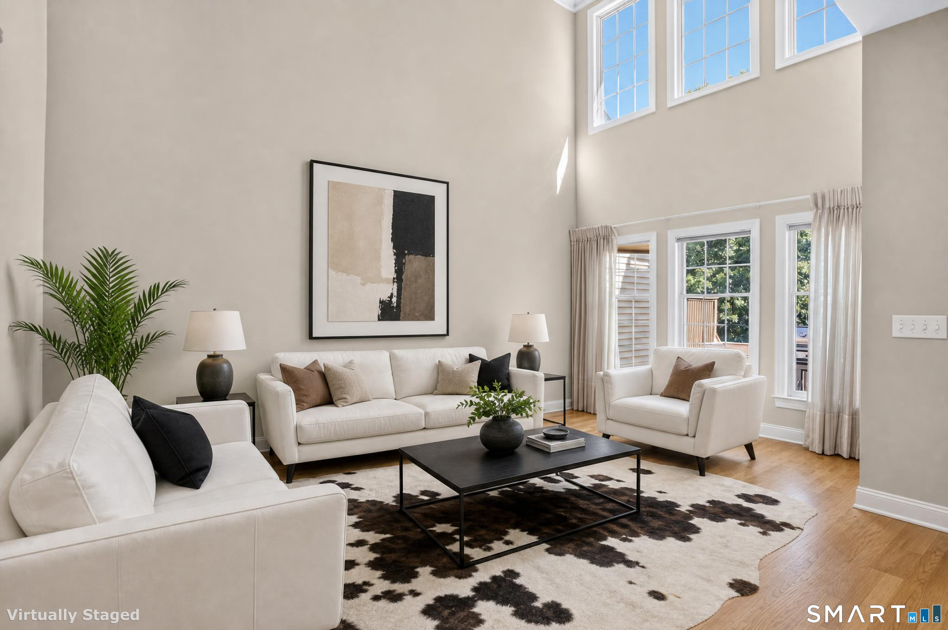 Virtually staged living room with a vaulted ceiling, tall windows, and white seating.