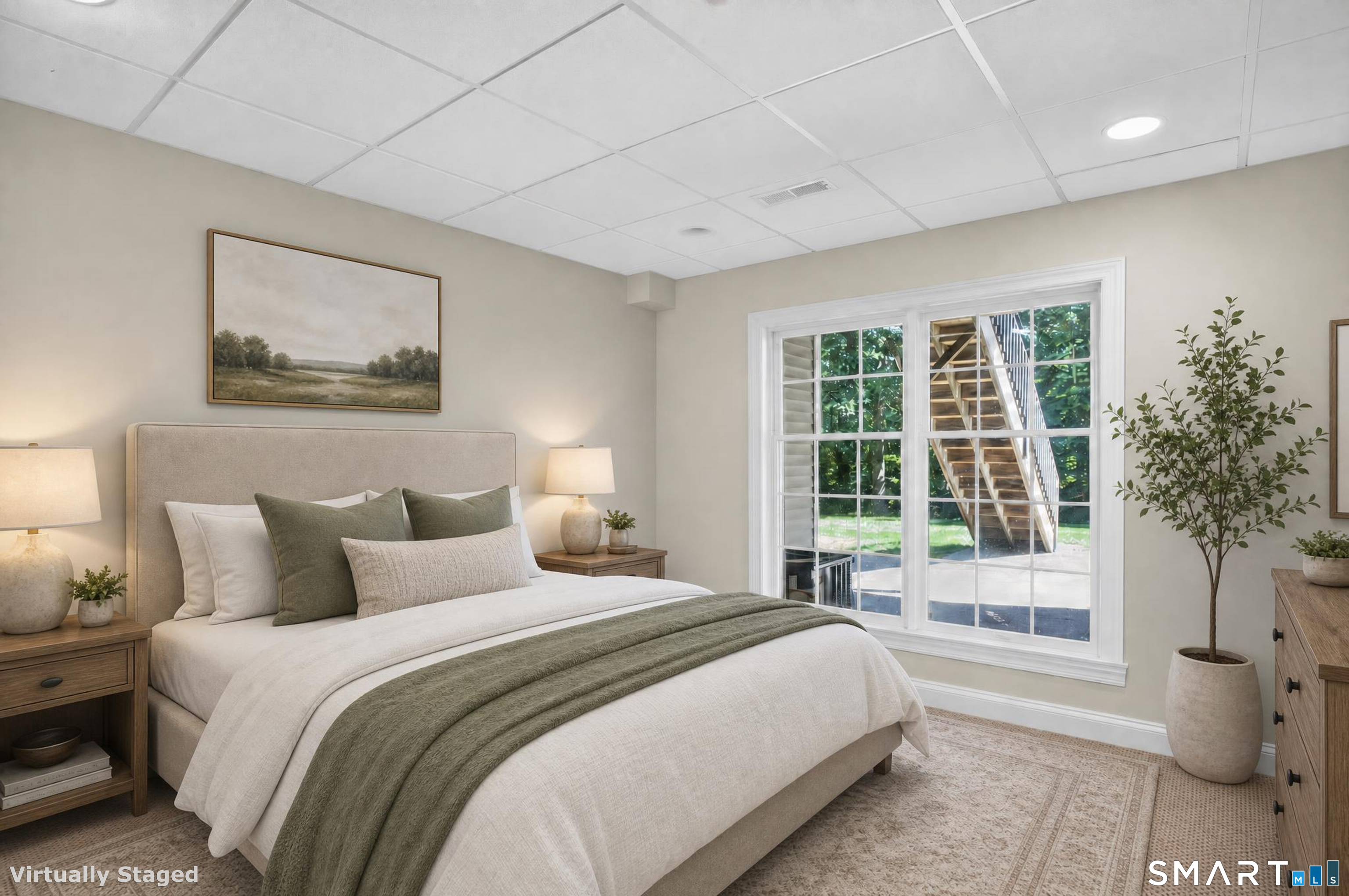 Staged bedroom with an upholstered bed and wide window overlooking greenery and an exterior staircase.