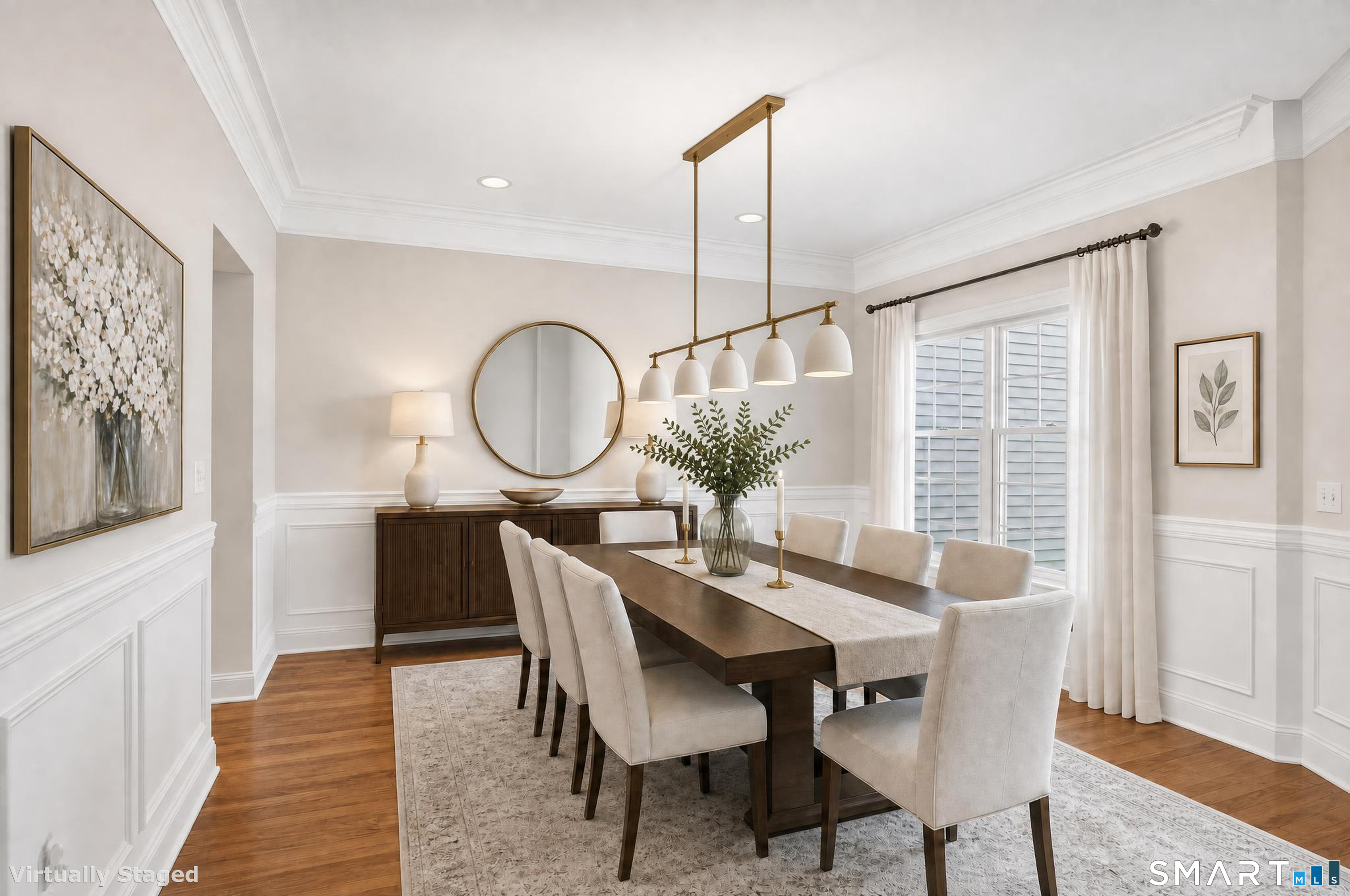 Dining room with a long wood table, upholstered chairs, and a brass pendant light.