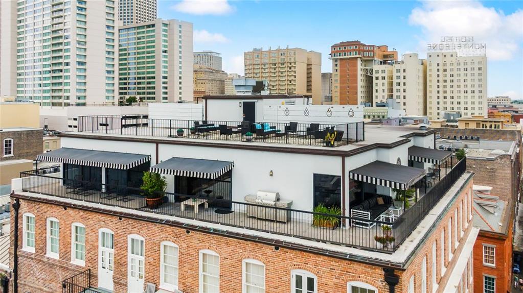 Rooftop terrace with striped awnings, outdoor seating, and a downtown skyline.