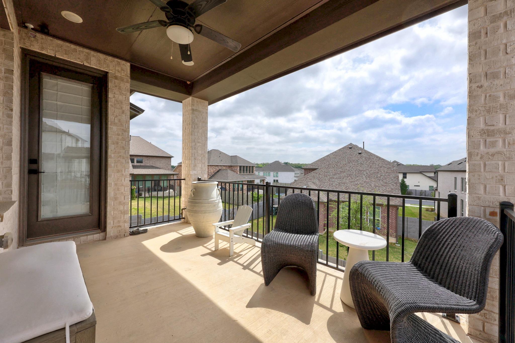 Covered patio with wicker chairs and a view of neighboring homes.