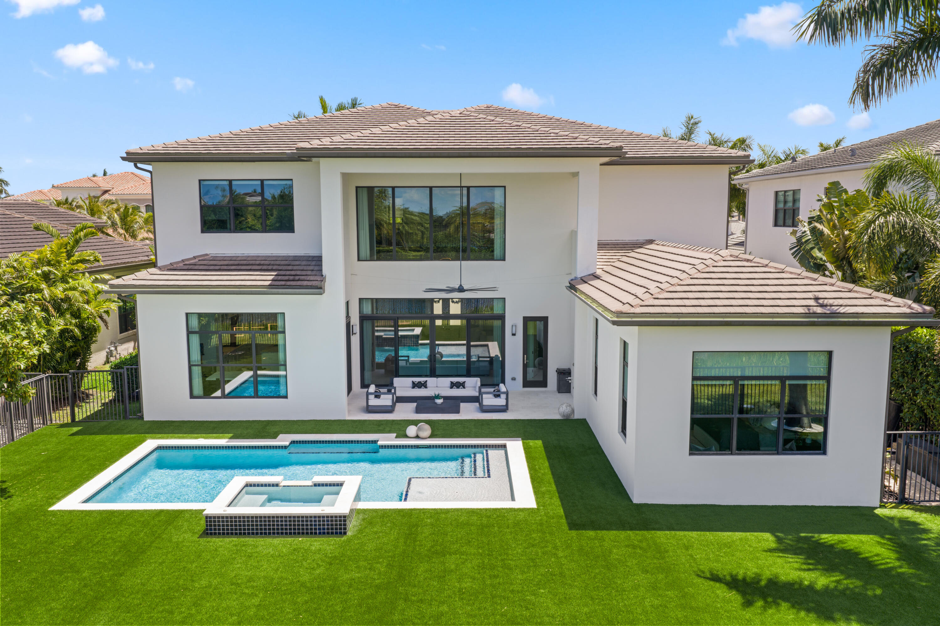 Modern two-story home's rear patio and pool, with a raised spa and manicured lawn.