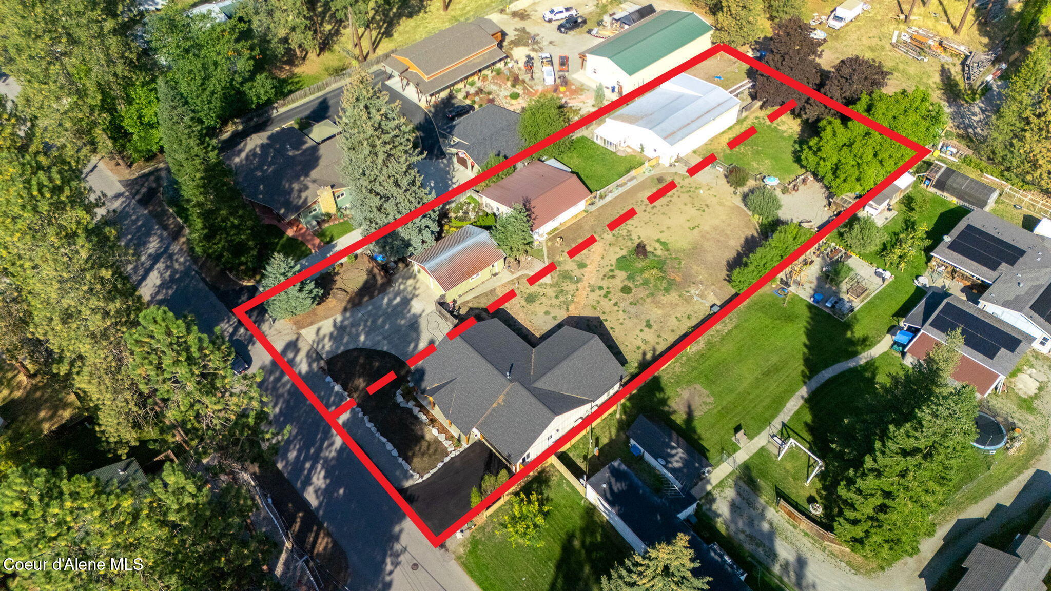 Aerial view of a house and large yard outlined in red, with several outbuildings.