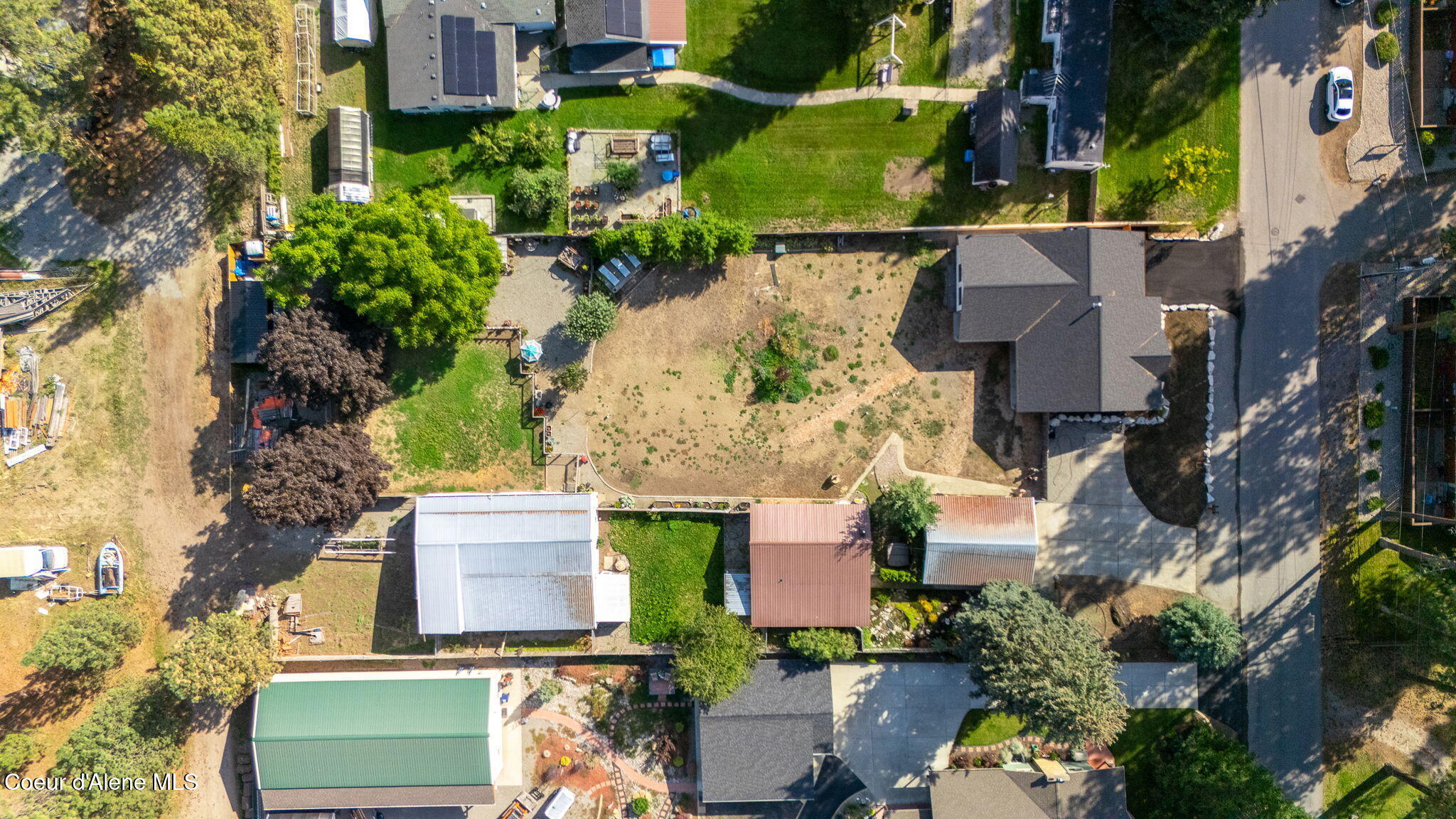 Aerial view of a home with a large, sparsely planted backyard and paved driveway.
