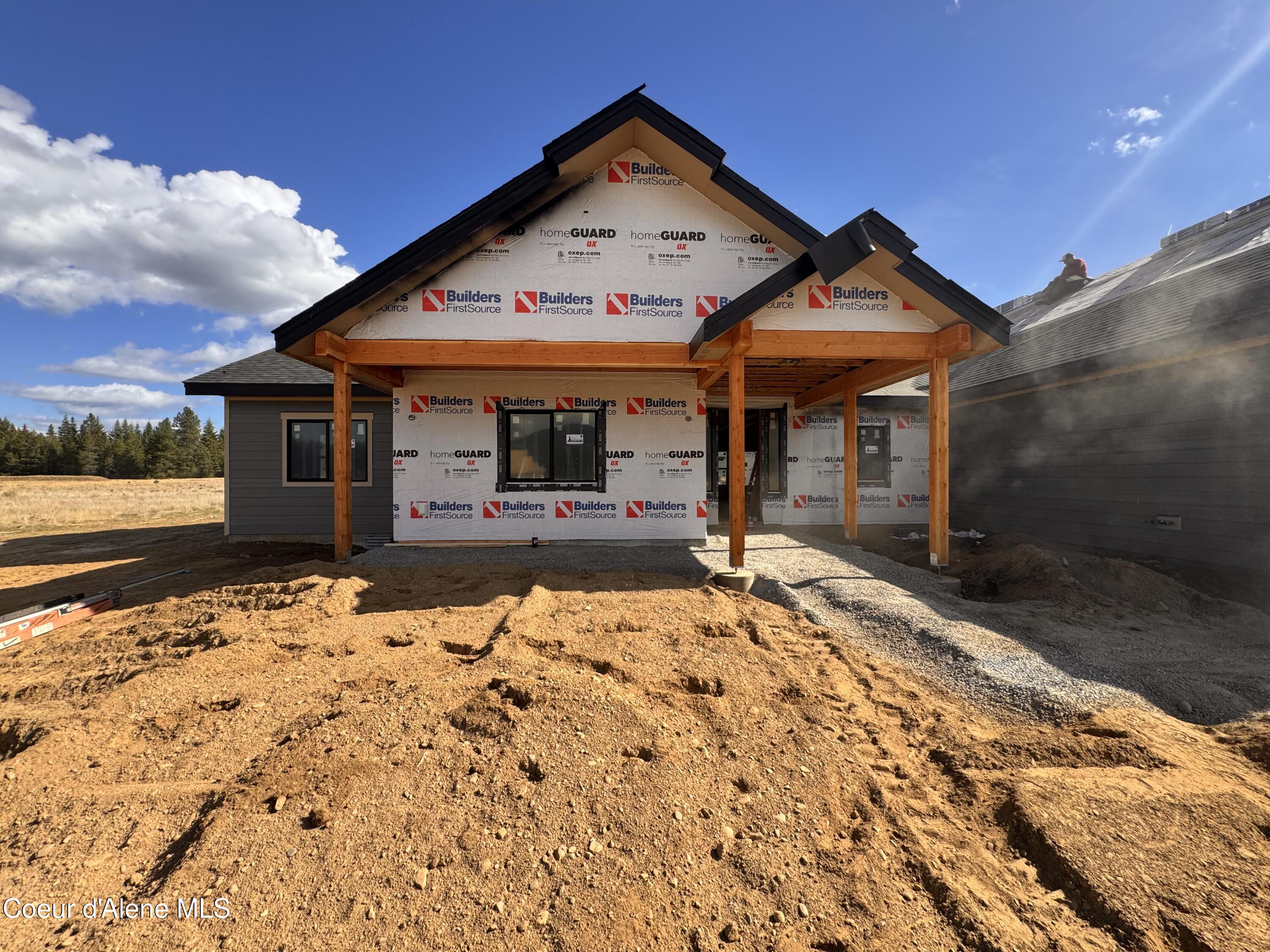 House under construction with exposed building wrap and timber porch supports.