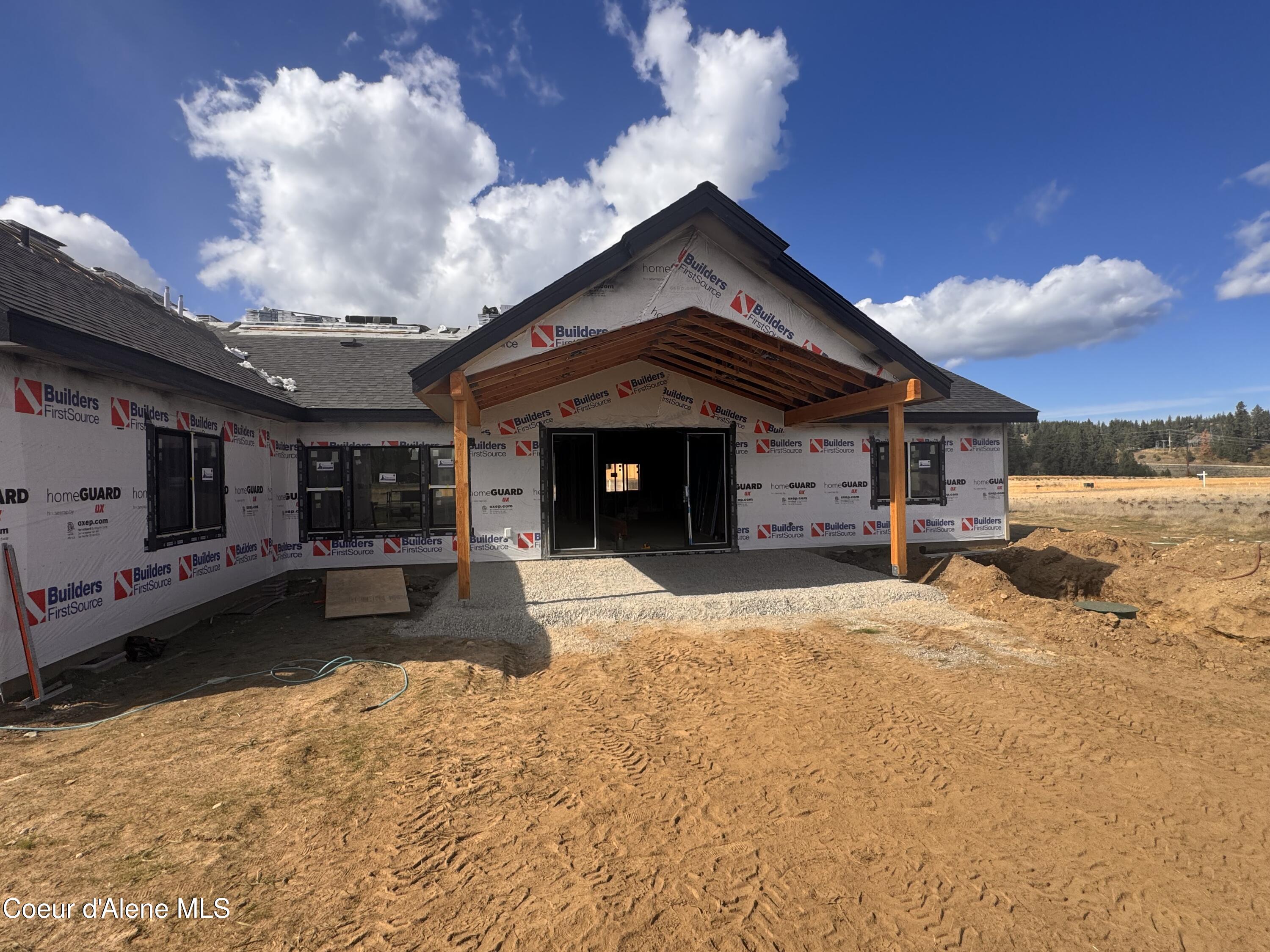 Home under construction with house wrap and unfinished timber porch framing.
