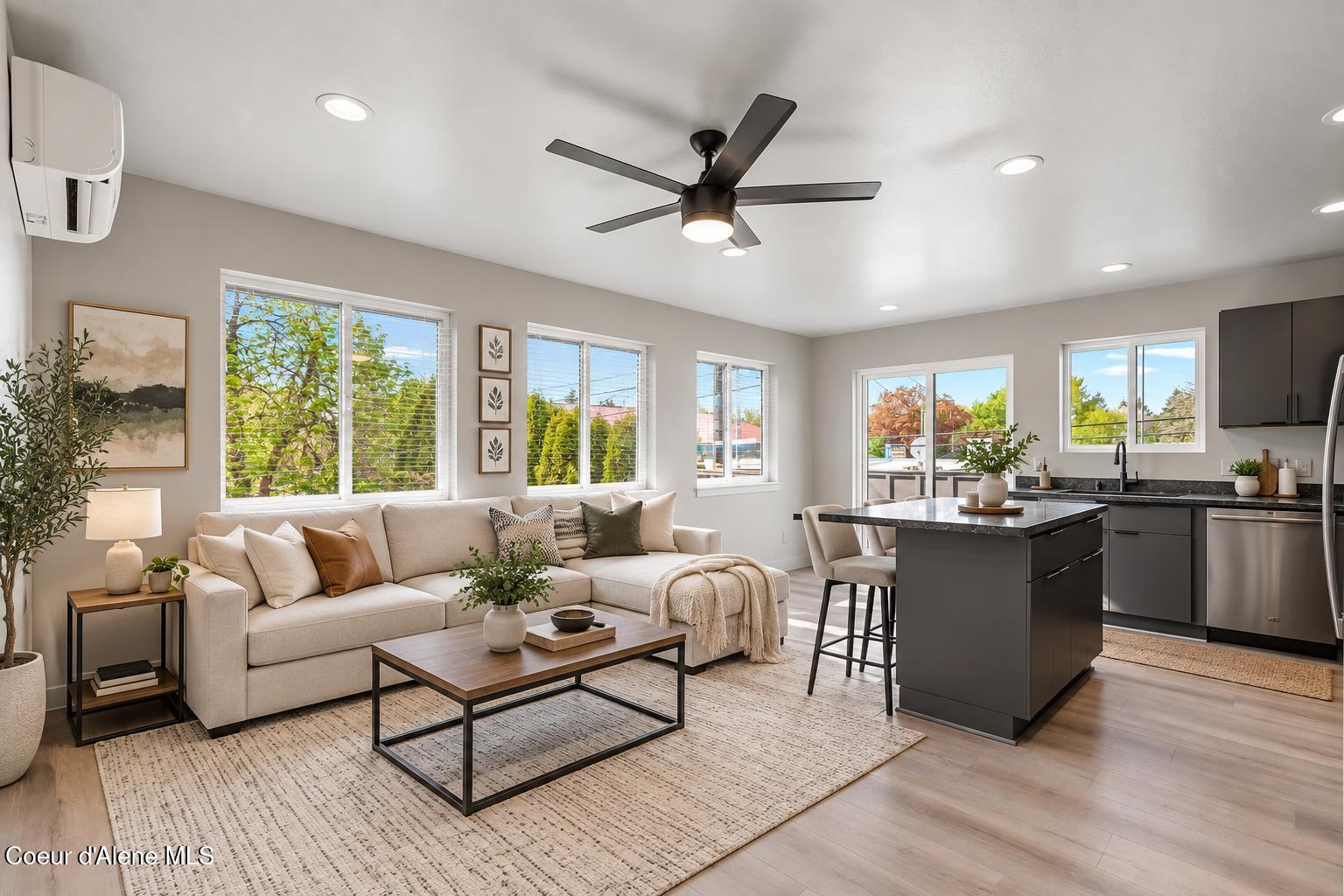 Open-plan living room and kitchen with a cream sectional, large windows, and a dark island.