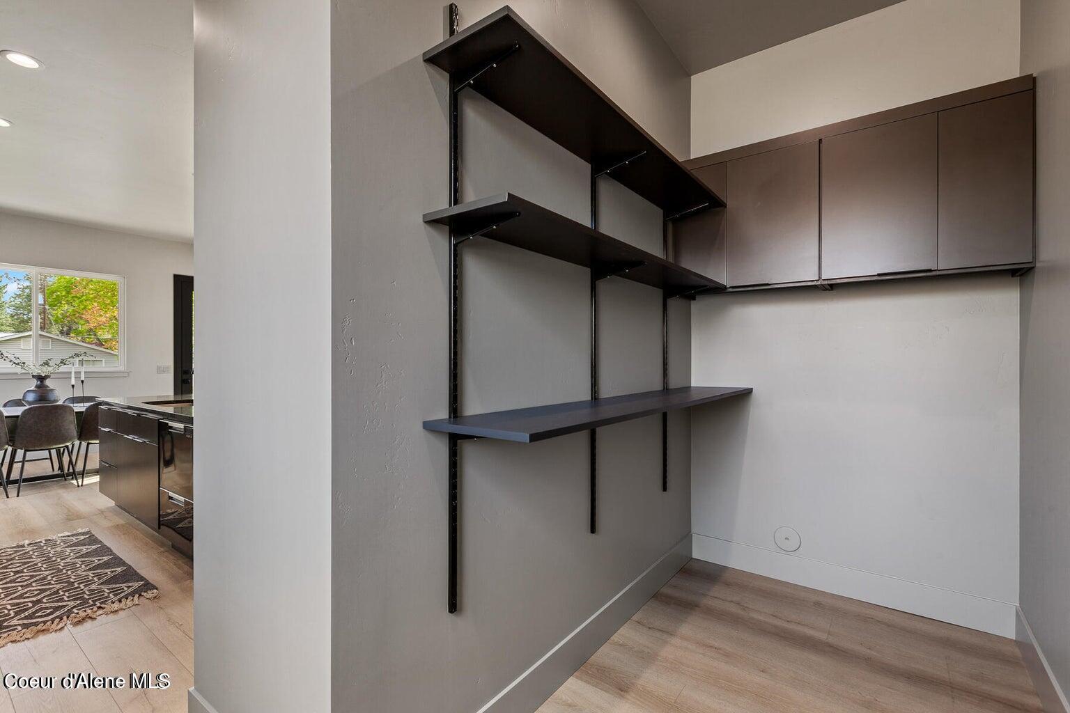 Built-in storage nook with dark adjustable shelves and upper cabinets beside the dining area.
