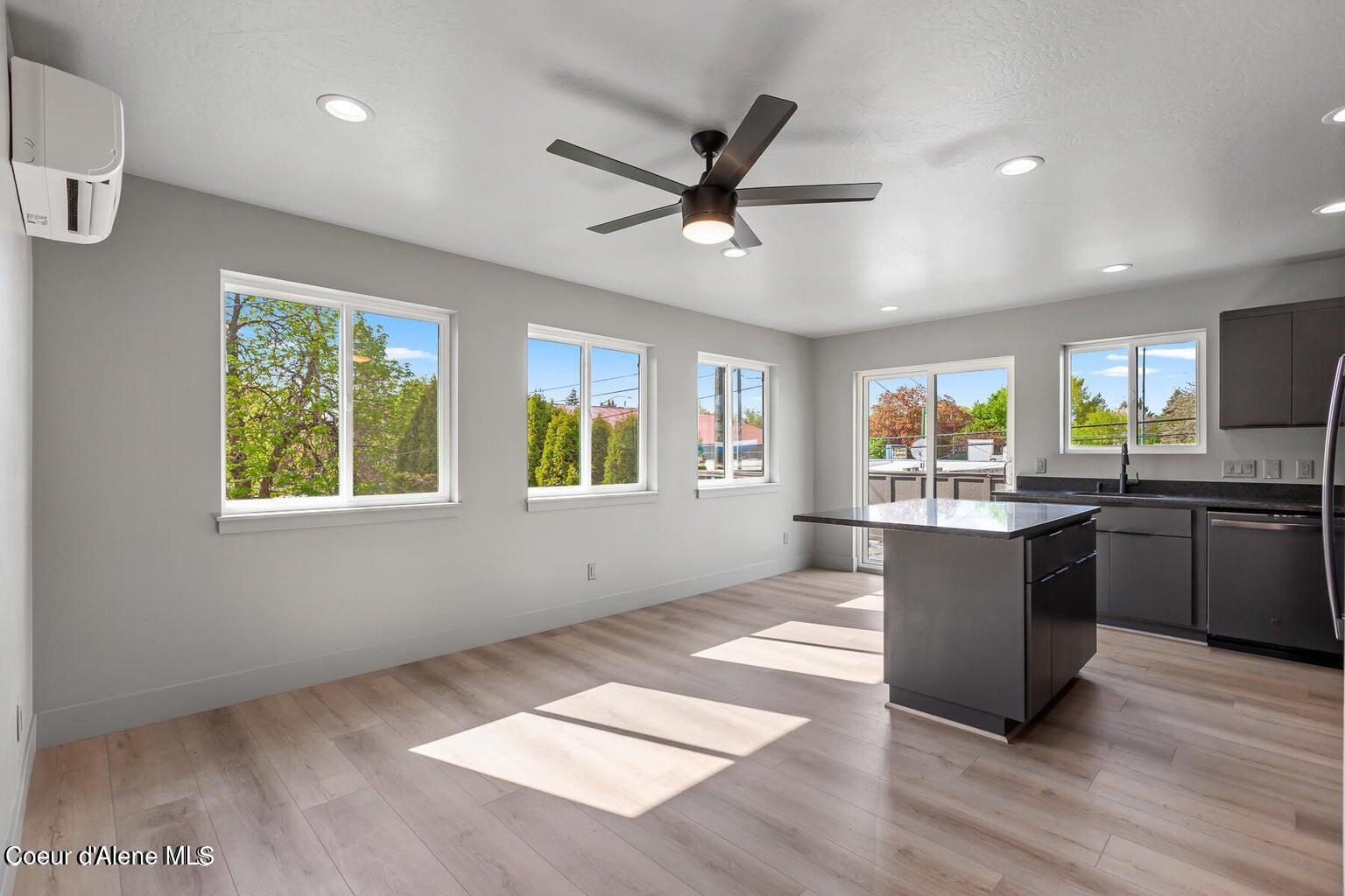 Vacant kitchen with a dark island, gray cabinetry, and sunlight streaming through multiple windows.
