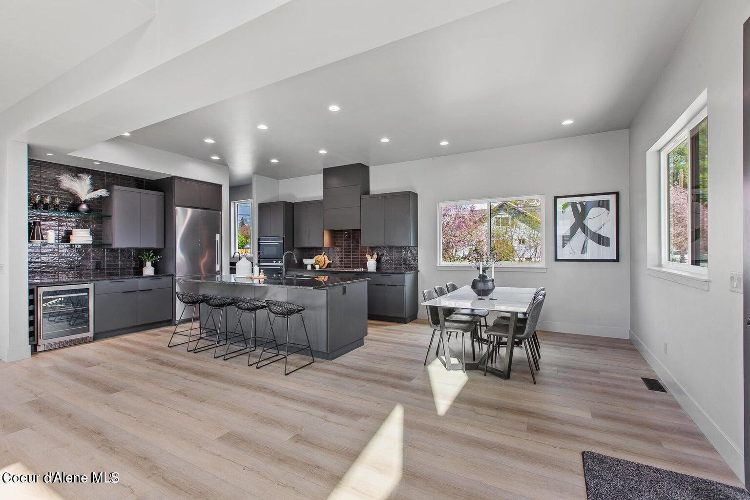Open-plan kitchen with dark cabinetry, a large island, and an adjacent dining area by large windows.