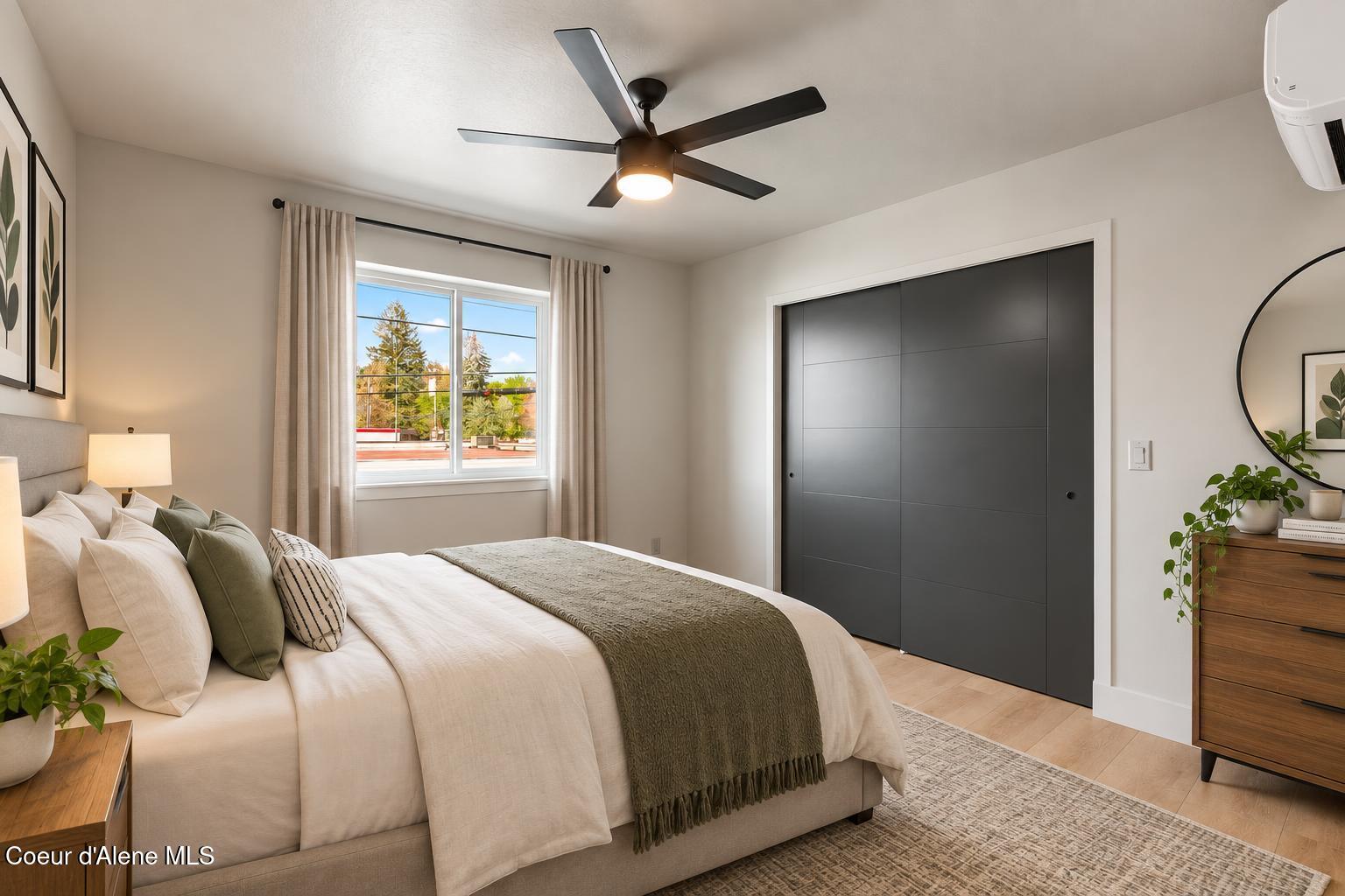 Furnished bedroom with dark sliding closet doors, a curtained window, and a black ceiling fan.