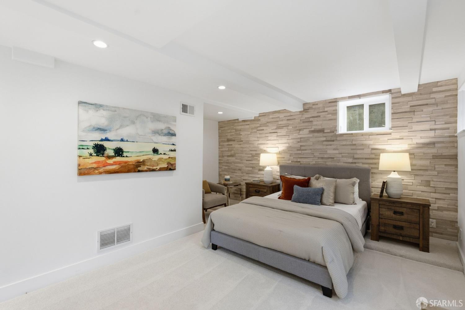 Staged bedroom with a gray bed, wood-look feature wall, matching bedside tables, and landscape painting.
