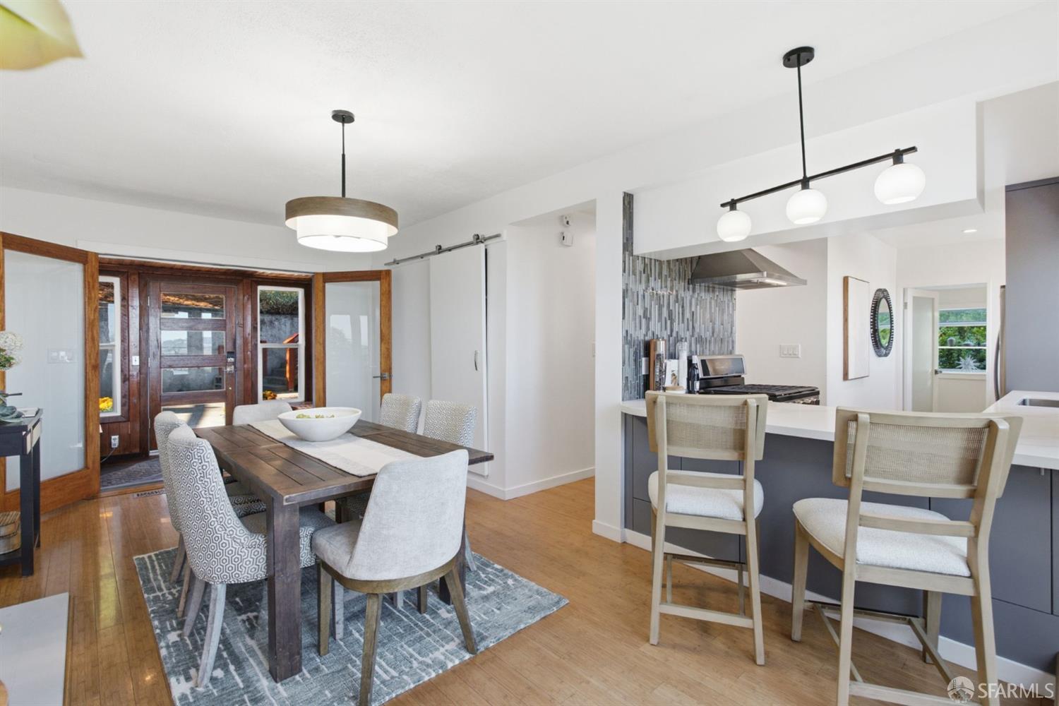 Dining area and kitchen with a wooden table, island seating, and wood-framed glass doors.