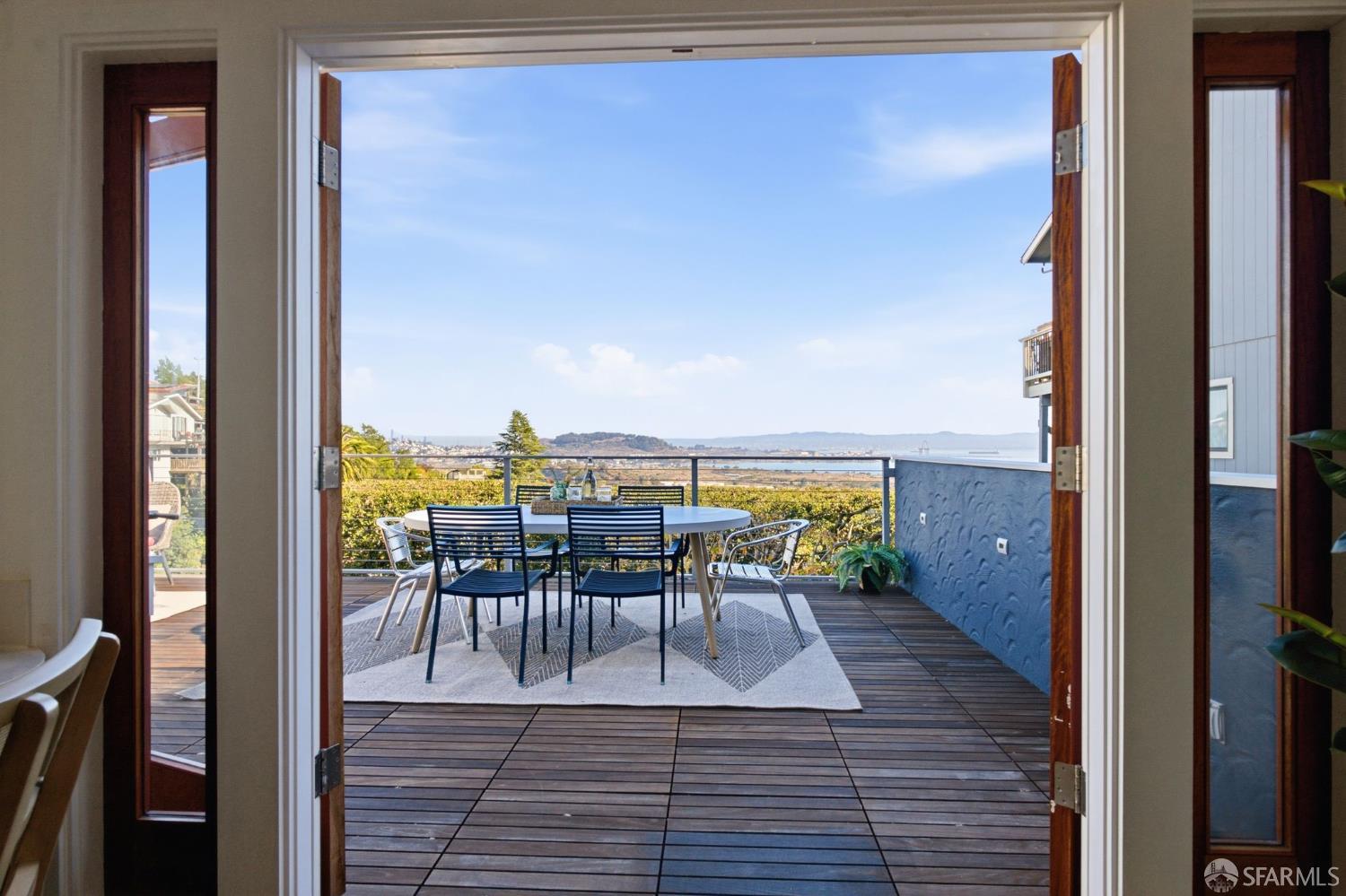 Rooftop deck with outdoor dining set and a wide bay view beyond the railing.