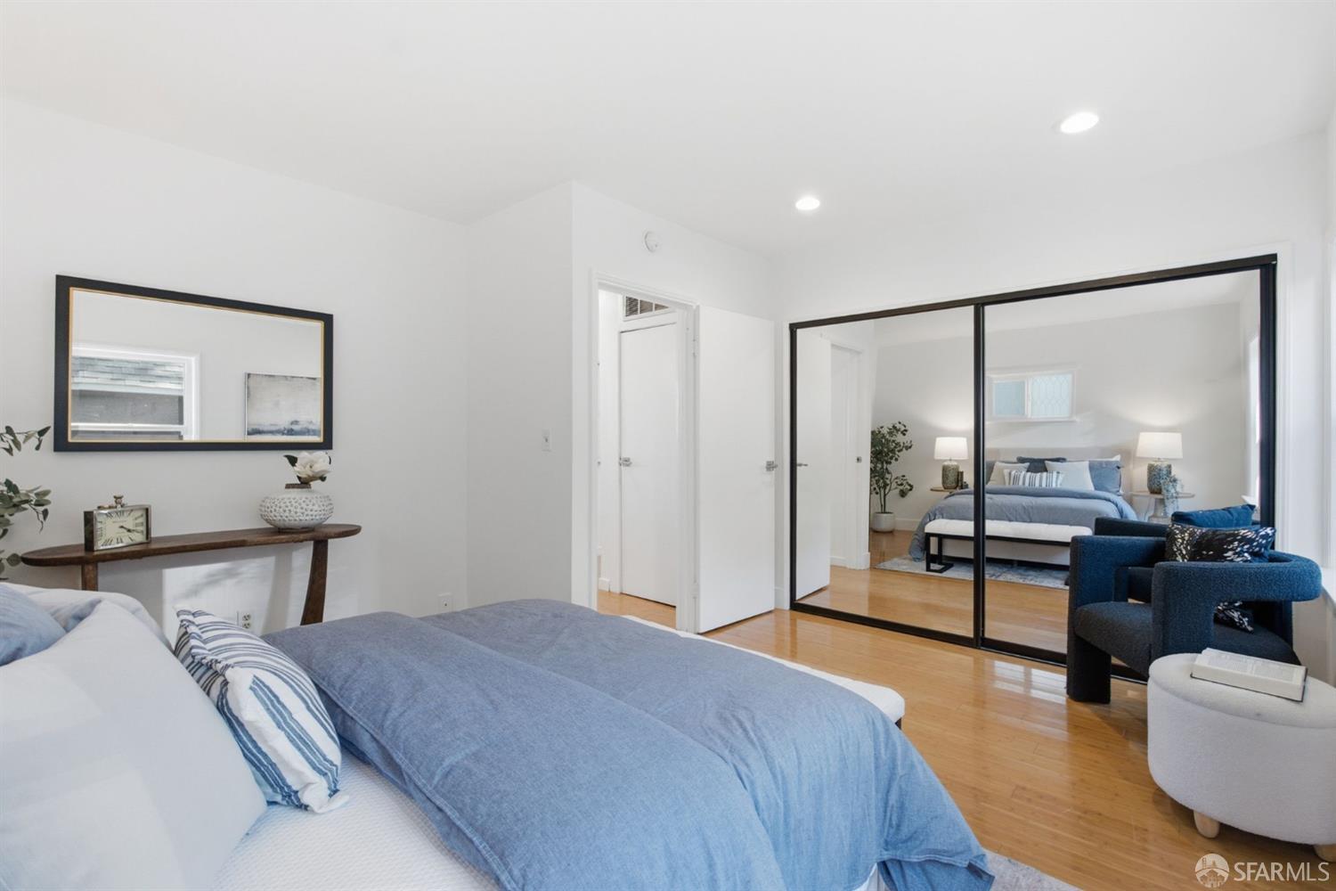 Bedroom with blue bedding and mirrored sliding doors opening onto a second sleeping area.