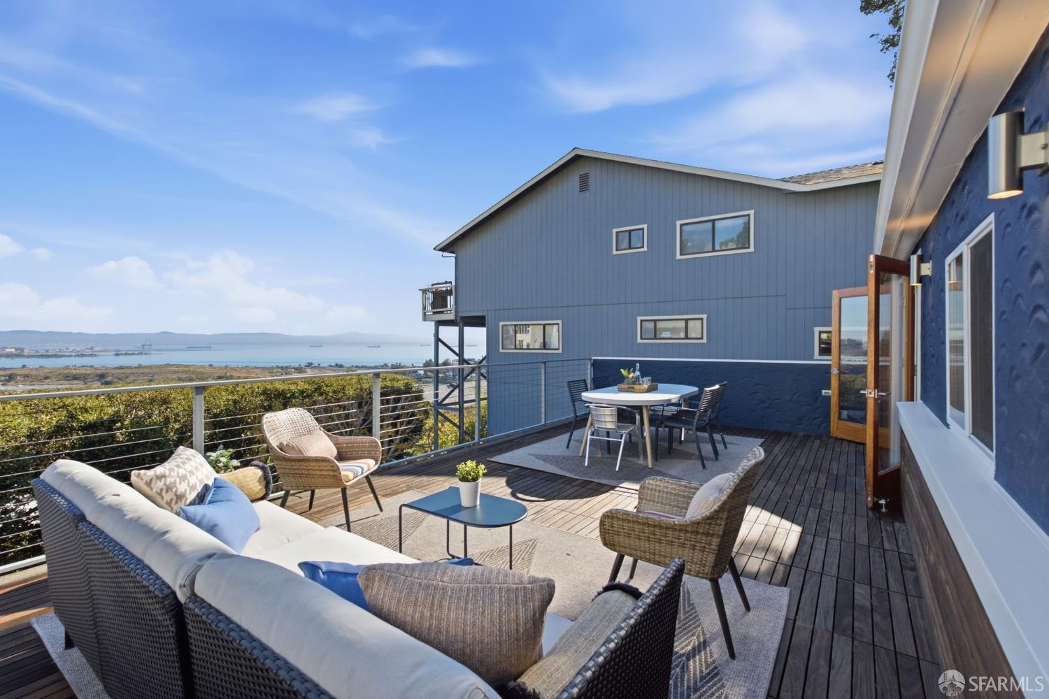 Furnished deck overlooking the water, with wicker seating and an outdoor dining area.