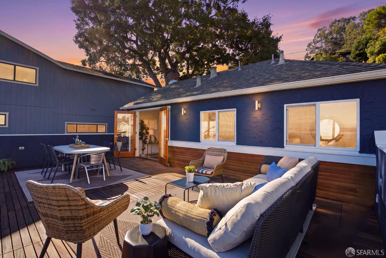Furnished outdoor deck with lounge seating and dining area at sunset.