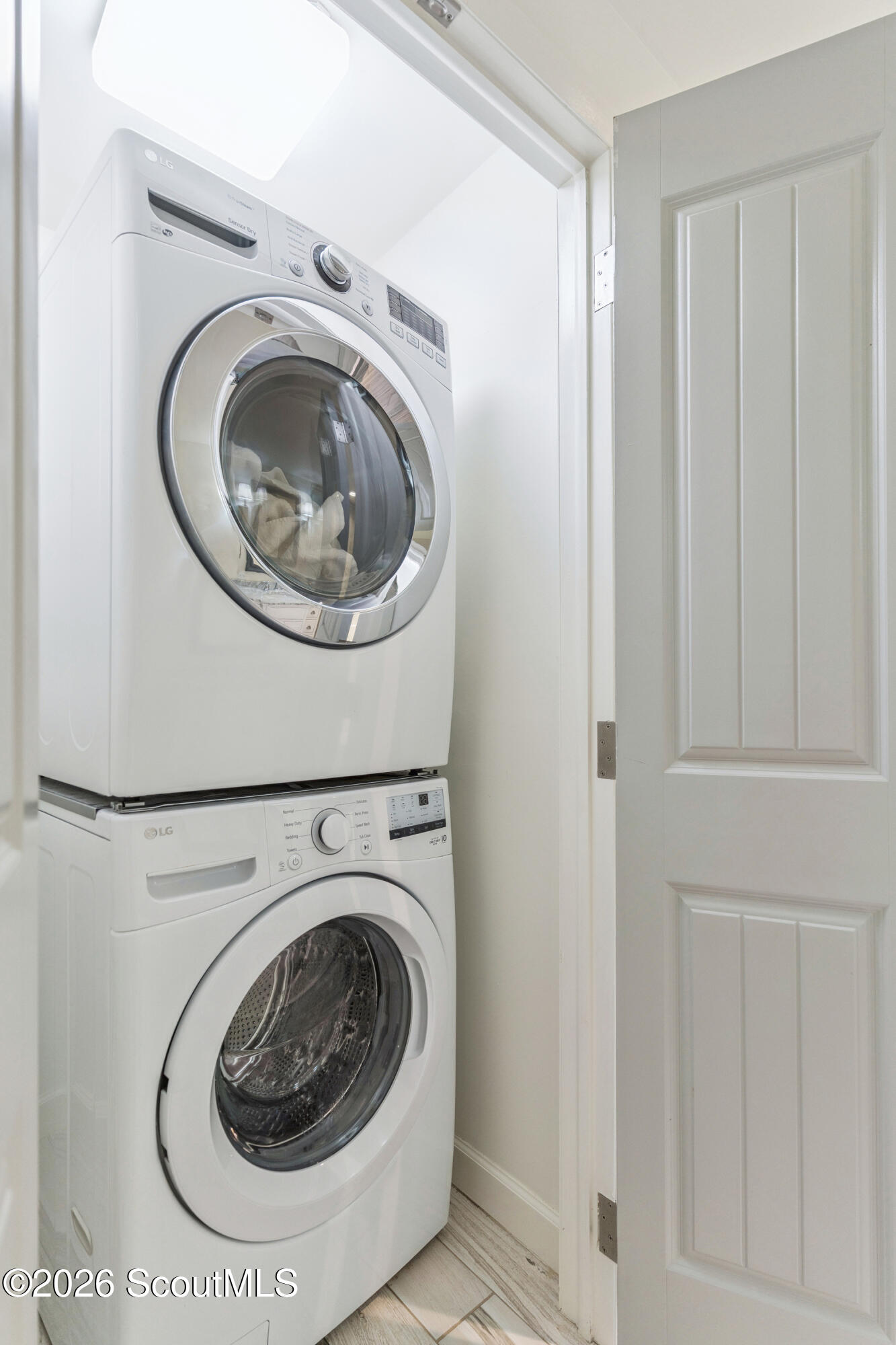 Stacked white LG washer and dryer in a compact laundry closet beside a paneled door.