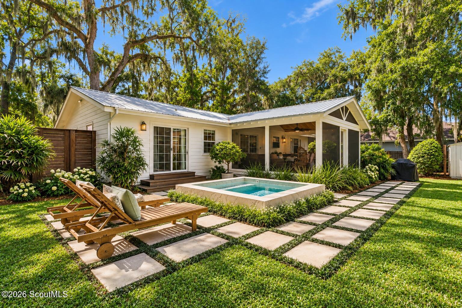 White home with a covered patio, small pool, and stepping-stone path through the landscaped backyard.