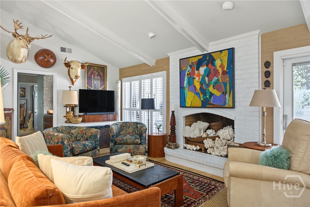 Living room with a white brick fireplace, colorful artwork, and patterned sofas.