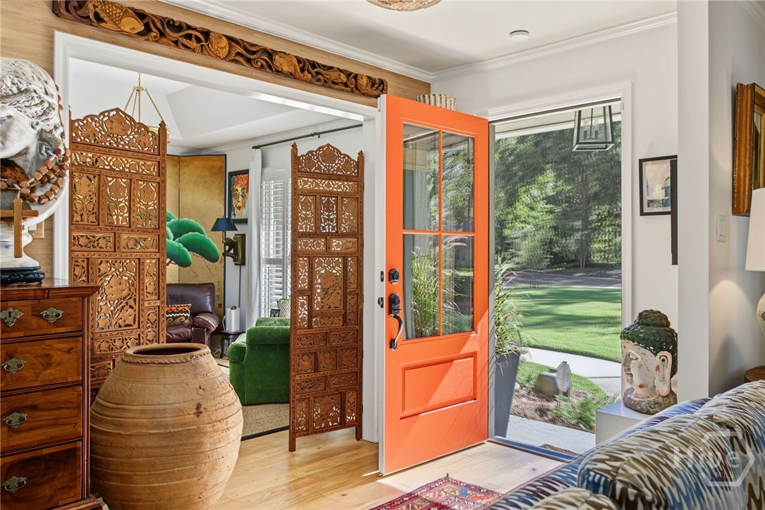 Furnished entryway with a bright orange open door and carved wooden screens.