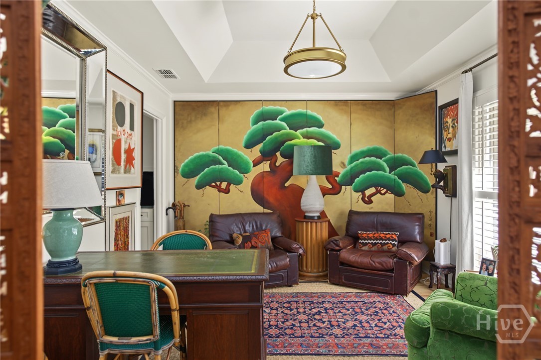 Sitting room with leather armchairs, green chairs, a patterned rug, and a colorful tree mural.