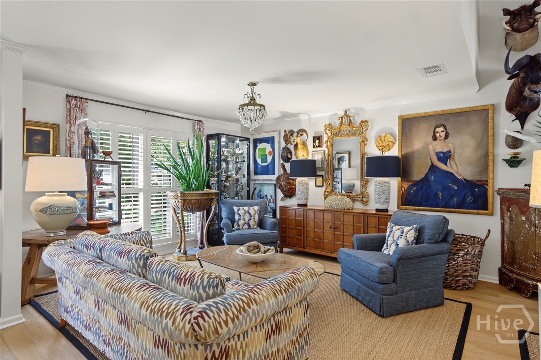 Furnished living room with patterned sofas, blue armchairs, and an eclectic collection of artwork and antiques.