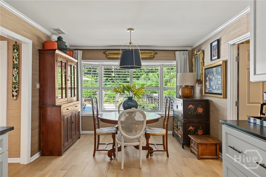 Dining room with a round glass-top table, cane-back chairs, and white plantation shutters.