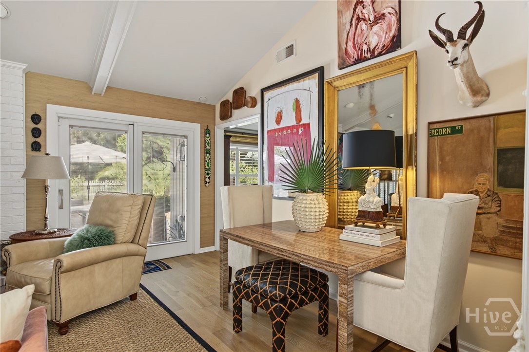 Furnished living room with a wood-topped table, white chairs, and a beige armchair.