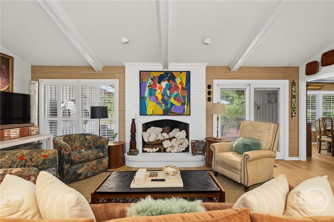 Living room with a white brick fireplace, colorful artwork, floral armchairs, and a beige leather recliner.