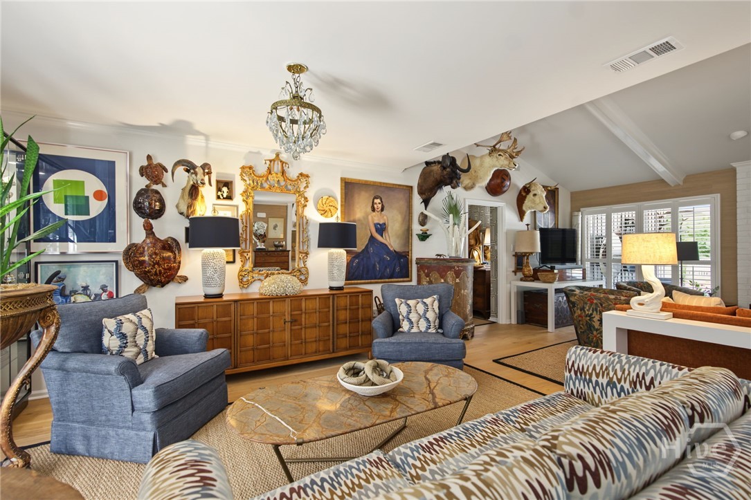 Living room with blue chairs, patterned sofas, an ornate mirror, and mounted animal heads.