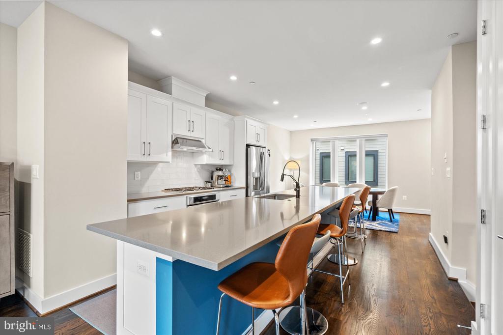 Modern kitchen with white cabinets, stainless steel appliances, and a long island with brown bar stools.