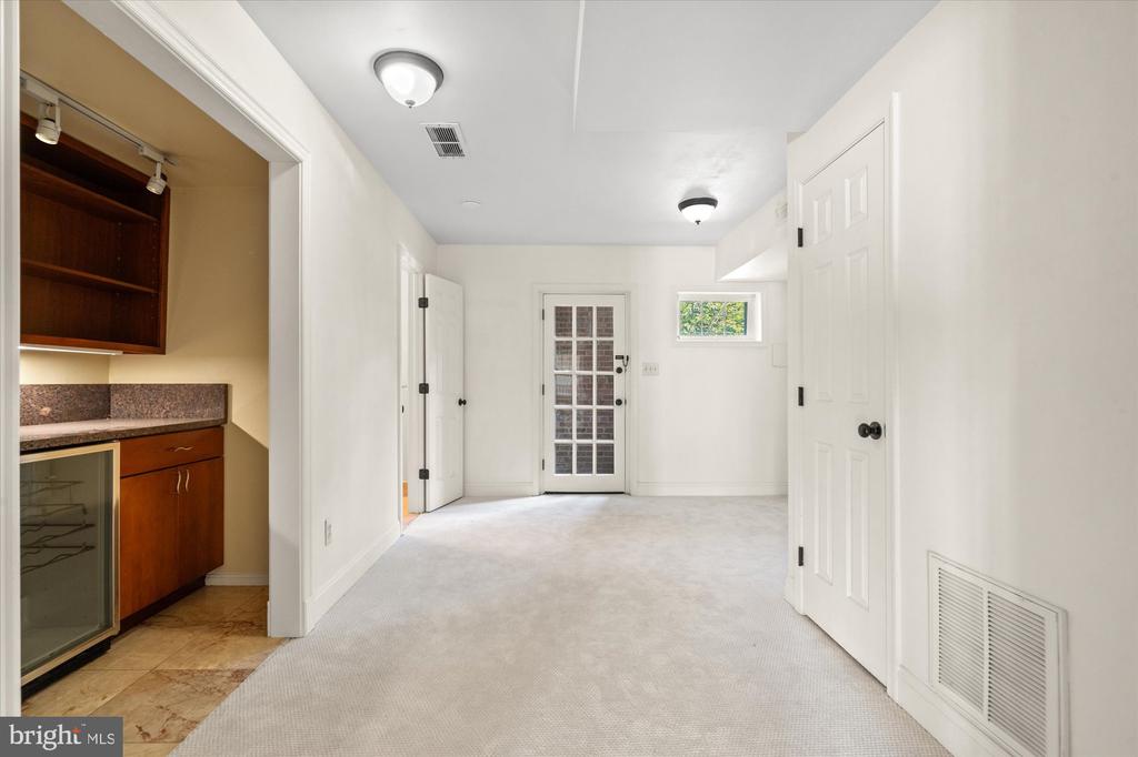 Carpeted room with a kitchenette alcove, glass-paneled door, and small window.