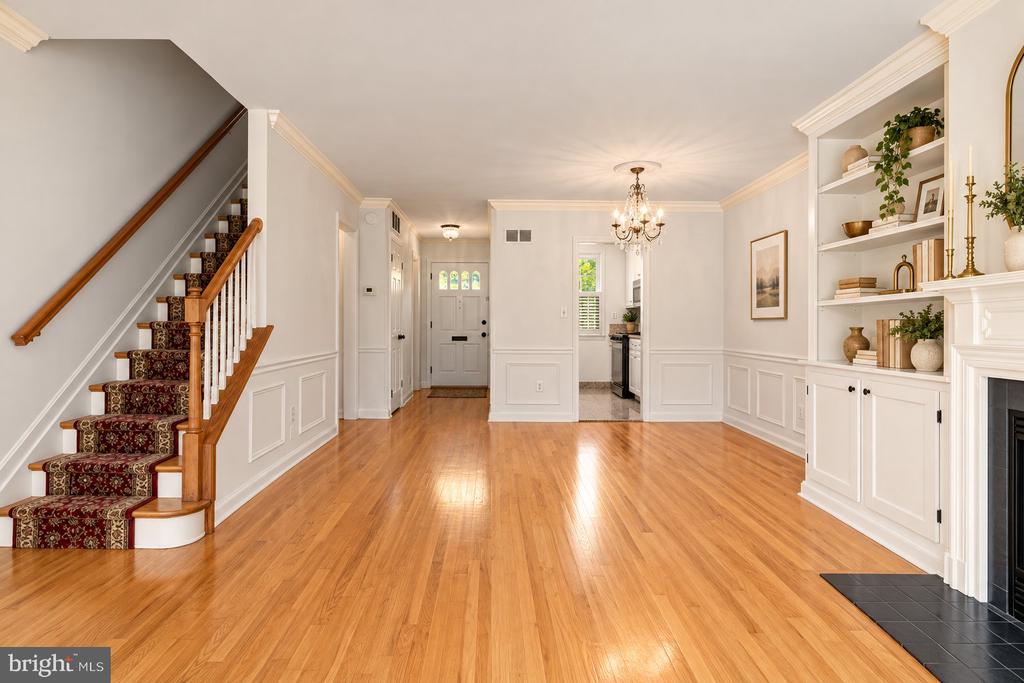 Entry and living area with hardwood floors, carpeted staircase, built-in shelves, and fireplace.
