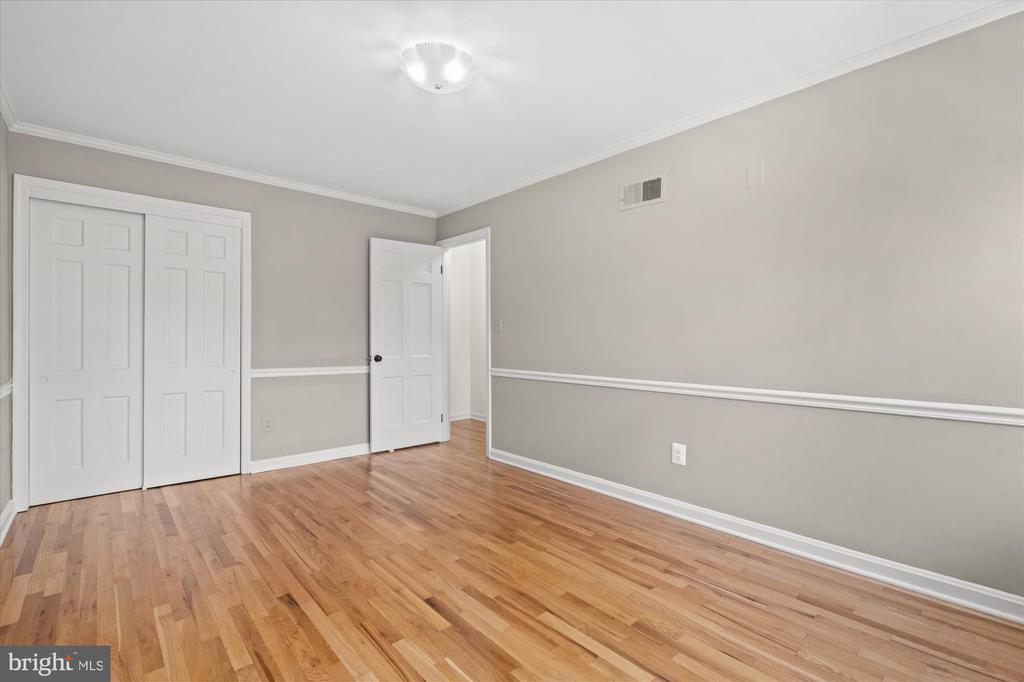 Empty room with hardwood floors, gray walls, and white closet doors.