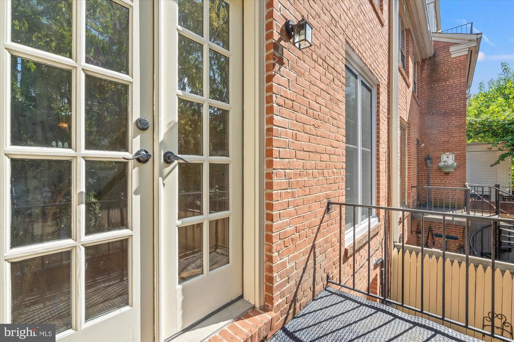 Brick home exterior with glass-paneled French doors opening onto a small raised balcony.